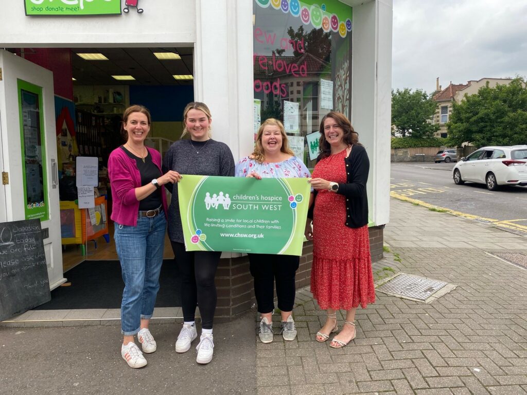 Paola, Charlotte, Debbie and Vicky holding up a banner outside Children's Hospice Southwest charity shop