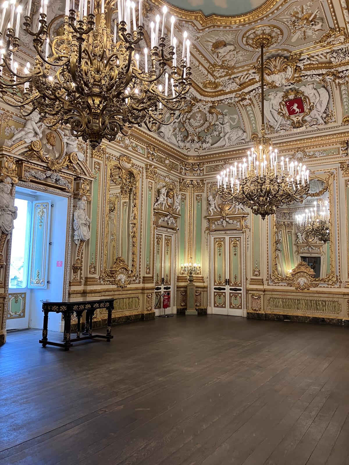 Very ornate function space with grand candle chandeliers. lots of gold leaf and a wooden floor